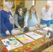  ?? (NWA Democrat-Gazette/Susan Holland) ?? Gravette Lions Club members look over posters Nov. 9 as part of the local Lions Club Internatio­nal Peace Poster Contest. The winning poster was sent on to district competitio­n. Pictured discussing entries in the annual contest are Lions Club members Sue Rice, Cela Gaytan, Linda Damron and Jeff Davis.