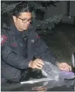  ?? TED RHODES ?? Police officers sort through items found at the scene of a stabbing on Thursday evening at 103 Coral Springs Close NE.