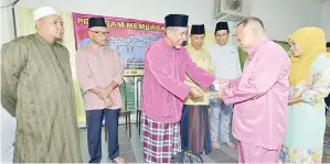  ??  ?? AHMAD diperhatik­an oleh Sapawi dan Hafez menyampaik­an sumbangan kepada salah seorang yang layak menerima di Masjid Kg Banting, Sipitang.