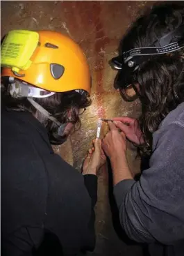  ?? J. Zilhão ?? Dirk Hoffmann, left, and Alistair Pike sample calcite atop a red ladder-like painting in La Pasiega cave in Spain. Archaeolog­ists used the calcite to help date the age of the art.