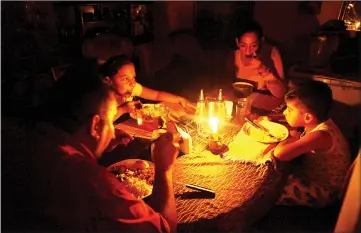  ??  ?? Lisney Albornoz (second right) and her family use a candle to illuminate the table while they dine, during a blackout in San Cristobal, Venezuela. — Reuters photo