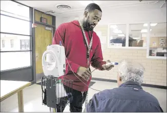  ?? DEBORAH CANNON / AMERICAN-STATESMAN ?? Rob Moore, a psychiatri­c nursing assistant at the Austin State Hospital, takes vitals on a patient Tuesday. The Texas Health and Human Services Commission said it will “continue to work with the governor’s office to ensure we take the best possible...