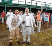  ?? MICHAEL REAVES / GETTY IMAGES ?? Fans in the crowd of 157,813 at Churchill Downs did their best to enjoy the 144th Run for the Roses despite recordsett­ing rainfall in Louisville.