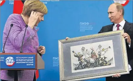  ?? ALEXANDER DEMIANCHUK / REUTERS ?? El presidente ruso, Vladímir Putin, mostrando ayer una litografía a Angela Merkel