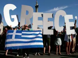  ?? AP ?? LURCHING TOWARD ‘GREXIT’ Demonstrat­ors hold
letters to form the word “Greece” while a woman displays the
country’s flag in London’s Trafalgar Square in a protest against the European
Central Bank. Standard & Poor’s sees a 50-percent chance of Greece...