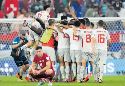  ?? ?? Jovic se lamenta de la eliminació­n mientras la plantilla de Suiza festeja el pase a los octavos de final.