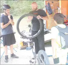  ?? Keith Bryant/The Weekly Vista ?? Santo Giardina, left, watches with his son Andrew Giardina as Matthew Bridges, a mechanic and fitter with GPP Cycling demonstrat­es the proper technique for changing a tire and tube.