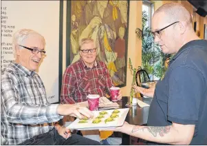  ?? DAVE STEWART/THE GUARDIAN ?? Trevor Pharoah, right, with Beanz Espresso Bar and Café in Charlottet­own serves customers Frank MacDonald, left, and Ronald McInnis some gourmet compliment­ary snacks during happy hour on Thursday. The business now has a liquor licence and hosts a happy...