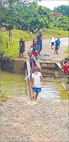  ?? Picture: VITI FM FACEBOOK PAGE ?? Children cross the steel frame of the washed-off bridge at Nairukuruk­u in Naitasiri that was damaged by heavy rain last Saturday.