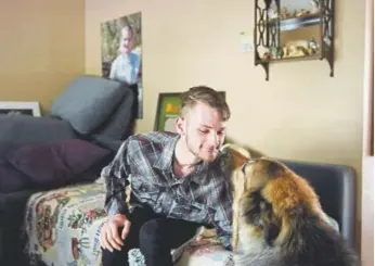  ??  ?? Stephen Morgan, sitting in his home in Broomfield, enjoys some time with Bear, a Macedonian shepherd that is a service dog for his adoptive brother Logan.