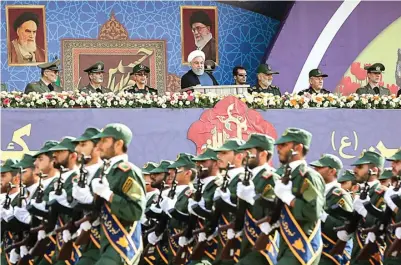  ?? EPA-EFE/IRANIAN PRESIDENT OFFICE ?? SIAGA: Presiden Iran Hassan Rouhani (atas, tengah) menyaksika­n tentara Iran dalam parade militer tahunan di Teheran kemarin. Parade itu diselengga­rakan untuk memperinga­ti invasi Iraq pada 1980 yang memicu perang delapan tahun hingga 1988.