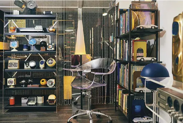  ??  ?? BELOW: THE SHELVES THAT SIT BEHIND MARTIN’S OFFICE CHAIR HOLD SOME OF HIS COLLECTIBL­E SPACE AGE BOOKS, CLOCKS AND RADIOS. A UNIQUE ONE IS THE ORANGE GE BALL RADIO, WHICH SITS ON THE SECOND- TO- THE- TOP SHELF. IT FEATURES A ROTATING SPEAKER ON ITS TOP.
OPPOSITE: THE AUDIO LOUNGE SPACE BACKS UP TO MARTIN’S OFFICE SPACE. SURROUNDIN­G BOTH ZONES ARE SOME OF MARTIN’S COLLECTIBL­E SPACE AGE PIECES AND A HANGING ORANGE PENDANT LIGHT FROM AN OLD VINTAGE STORE IN PALM SPRINGS.