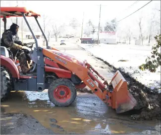  ?? Brodie Johnson • Times-Herald ?? The Forrest City Water Department makes repairs today to a main line along Dillard Avenue. Demetrick Haggins, with the FCWD, uses a tractor with a front loader to move dirt and asphalt away from the site so the hole can be refilled and the roadway patched.