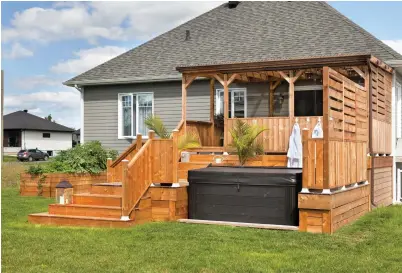  ??  ?? Le spa s'insère parfaiteme­nt dans la terrasse en bois traité. Celle-ci a été conçue sur mesure pour épouser la forme du bain à remous, en plus de créer un deuxième palier autour de ce dernier.