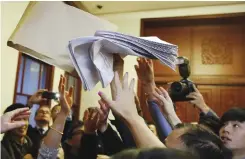  ?? — AP ?? HONG KONG: Reporters try to grab copies of press statements of interpreta­tion of Hong Kong’s Basic Law released by an officer before a press conference at the Great Hall of the People in Beijing yesterday.