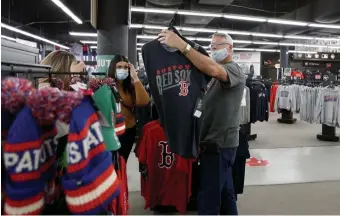  ?? MARY SCHWALM / BOSTON HERALD ?? POPULAR OPTION: Jeff Woodruff, visiting from Oklahoma, talks with his family about buying the right Red Sox shirt at the team store on Jersey Street.