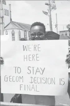  ??  ?? A citizen holds a cardboard sign while standing with others at one of the barricades placed near the High Court yesterday