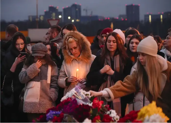  ?? BILD: ALEXANDER ZEMLIANICH­ENKO ?? Människor kommer med blommor och ljus till en upprättad minnesplat­s invid konserthus­et i Moskvas västra utkant.