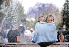  ??  ?? Niños se cubren tras bañarse en las fuentes de la Alameda Central.