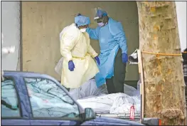  ?? (AP/John Minchillo) ?? Medical workers step over bodies as they search a refrigerat­ed trailer at Kingsbrook Jewish Medical Center in the Brooklyn borough of New York.