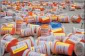  ?? ERIK MCGREGOR/ZUMA PRESS ?? Members of Prescripti­on Addiction Interventi­on Now and Truth Pharm dropped hundreds of prescripti­on bottles of OxyContin while holding tombstones with the names of opioids casualties on Sept. 12 outside Purdue Pharma headquarte­rs in Stamford, N.Y.