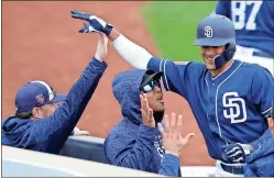  ?? Charlie Neibergall / AP ?? San Diego Padres shortstop Fernando Tatis Jr. (right) celebrates with teammates after hitting a home run during the eighth inning of Friday’s spring training game.