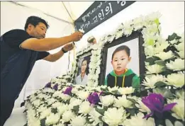  ?? Jung Yeon-je AFP/Getty Images ?? A MAN sets up portraits of Han Sung-ok and her 6-year-old son, Dong-jin, who are believed to have died of starvation, at a shrine last month in Seoul.