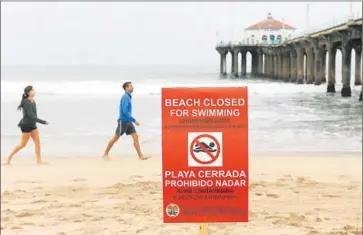  ?? Photog r aphs by Christina House For The Times ?? SIGNS warn people not to swim in Manhattan Beach after the appearance of tar- like substance along the shoreline. As much as 21,000 gallons of oil were spilled when a pipe burst in Santa Barbara County on May 19.