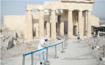  ??  ?? An employee places barriers in front of Propylaea at the Acropolis hill of Athens this week. Greece has reopened the Acropolis and other ancient sites.