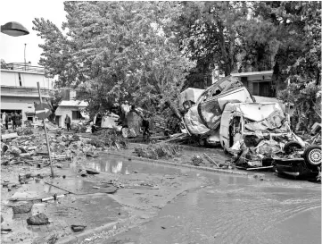  ??  ?? Car wreckages are piled up in a flooded street of Mandra, northwest of Athens after heavy overnight rainfall. — AFP photo