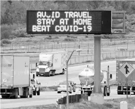  ?? MARK J. TERRILL/AP ?? Signs along interstate­s may urge motorists to stay at home, but truckers must stay on the job in order for America to beat COVID-19.