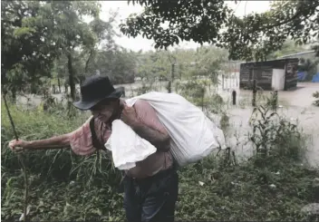  ?? ASSOCIATED PRESS ?? ANGEL ZAVALA, 72, CARRIES A FEW BELONGINGS he was able to salvage from his home in a flooded neighborho­od of Jehova, Honduras, Wednesday.