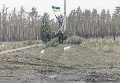  ?? ?? A man installs a Ukrainian flag on a memorial for Ukrainian soldiers in Kramatorsk yesterday