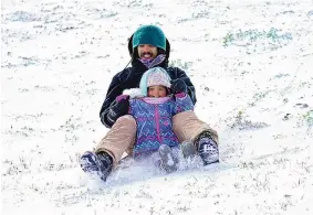  ?? DAVID J. PHIILLIP/ASSOCIATED PRESS ?? Robert Savannah and his daughter Sophia, 4, slide down a snow-covered hill Monday in Houston, Texas. The storm prompted a power emergency in the state.