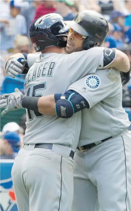  ?? — THE CANADIAN PRESS ?? Kyle Seager of the Mariners. left, embraces teammate Nelson Cruz after Cruz belted a three-run homer in the eighth inning against the Blue Jays on Saturday.