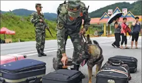  ?? LIN YIGUANG / XINHUA ?? Narcotics control officers inspect passengers’ luggage at a border area in Yunnan province.