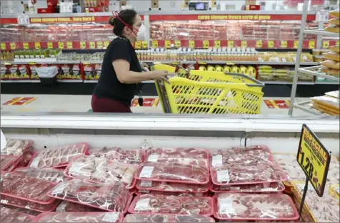  ?? LM Otero/Associated Press ?? Amid concerns about the spread of COVID-19, a shopper wears a mask as she walks through the meat products April 29 at a grocery store in Dallas.