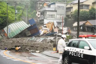  ?? Naoya Osato / Kyodo News ?? Debris from a mudslide covers a street in Atami, about 60 miles southwest of Tokyo. An intensive search was under way for as many as 20 people who were missing after the slide buried dozens of homes.