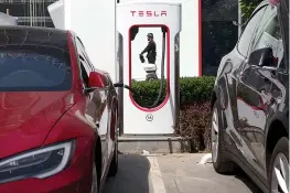  ?? AP Photo/
Ng Han Guan, File ?? n A security guard moves past an electric vehicle charging station April 14 in Beijing. Momentum is building worldwide for electric cars thanks to rising government fuel economy standards and climate concerns. Automakers are jumping on board. But...