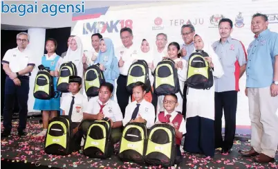  ??  ?? RAHMAN (enam kiri) bersama tetamu kehormat lain merakamkan gambar kenangan bersama pelajar yang menerima bantuan persekolah­an.