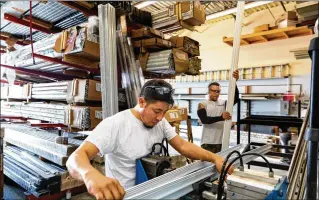  ?? GREG LOVETT / THE PALM BEACH POST ?? Raymundo Orozco (left) and Enrique Rodriguez of Guardian Storm Protection work on hurricane shutter tracks in suburban West Palm Beach. The tariffs on steel and aluminum are forcing delays and increases in the costs for hurricane shutters across South Florida.