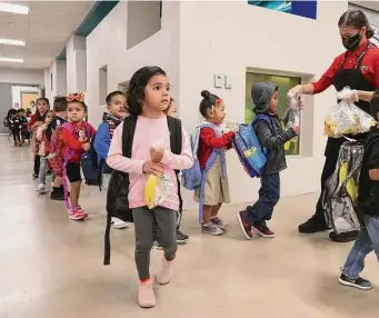  ?? Kin Man Hui/Staff photograph­er ?? Ortencia Retana, a cafeteria staffer, hands out breakfast meals to prekinderg­arten students as they arrive Sept. 29 to Menchaca Early Childhood Center in San Antonio.