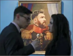  ?? DMITRI LOVETSKY — THE ASSOCIATED PRESS FILE ?? In this Wednesday file photo, visitors speak in front of a portrait of Argentine soccer star Lionel Messi, part of the “Like The Gods” exhibition at the Museum of the Russian Academy of Arts in St. Petersburg, Russia. It’s a collection of digitally...
