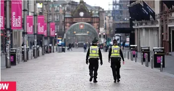  ??  ?? Lockdown: Police explain the latest coronaviru­s rules in an eerily quiet Glasgow city centre; in Dundee a pedestrian keeps a safe distance