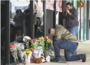  ?? Curtis Compton / Atlanta Journal-Constituti­on ?? Latrelle Rolling (left) and Jessica Lang leave flowers outside a massage business in Acworth, Ga., where four people were killed last week.