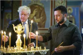  ?? UKRAINIAN PRESIDENTI­AL PRESS OFFICE VIA AP ?? Ukrainian President Volodymyr Zelenskyy, right, and Britain’s Prime Minister Boris Johnson light candles as they visit the Mikhailovs­ky Zlatoverkh­y Cathedral (St. Michael’s Golden-domed Cathedral) in Kyiv, Ukraine, Friday.