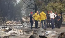  ??  ?? ASSESSING THE AFTERMATH: California Gov. Gavin Newsom, wearing a white shirt, tours a home destroyed by the Kincade fire on Friday in Geyservill­e, Calif. Below, firefighte­rs examine a burned-down low-voltage power pole during the Tick fire in Santa Clarita, Calif.