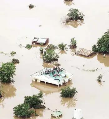  ?? RICK EMENAKET / MISSIoN AvIATIoN FElloWShIP / AFP ?? People take shelter on a roof in Beira, Mozambique, after a cyclone ripped through the region, causing “massive and horrifying” destructio­n. The Red Cross said 90 per cent of Beira and its surrounds are damaged or destroyed.