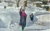  ??  ?? Women carrying drinking water walk on a snow covered road as normal life is gradually returning after heavy snowfall in the Valley, at Gund area of Ganderbal district of Central Kashmir, on Sunday