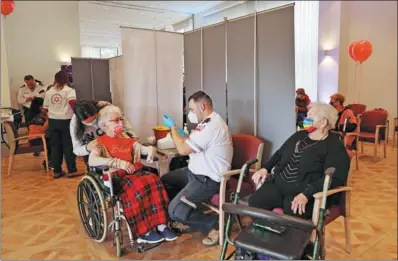  ?? RONEN ZVULUN / REUTERS ?? Residents of an assisted living facility receive their booster shot of the vaccinatio­n against COVID-19 during a party celebratin­g the residents receiving their second dose of the vaccine in Netanya, Israel, on Tuesday.